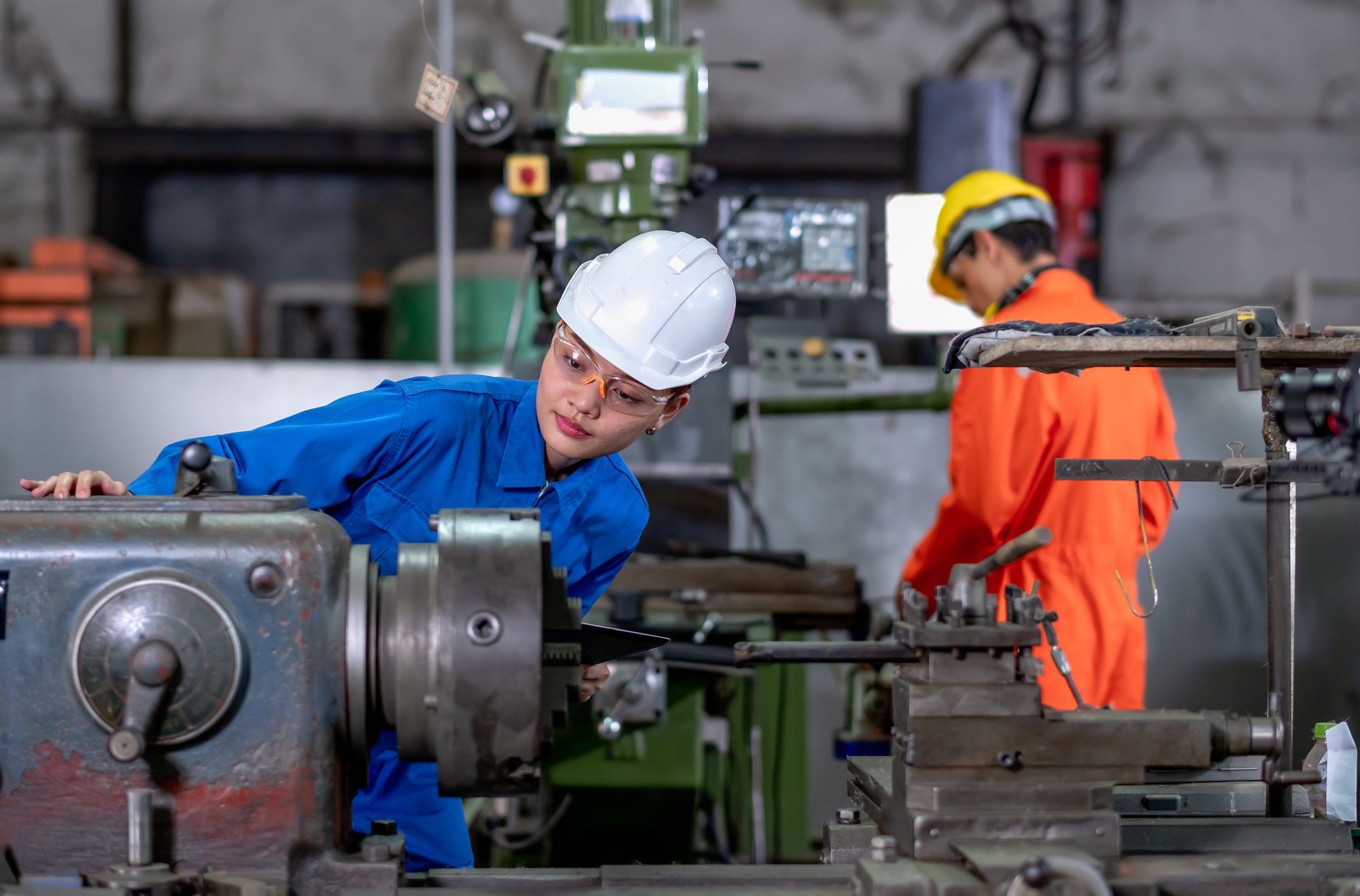 Asian factory worker woman look to part of the machine and inspect the function machine
